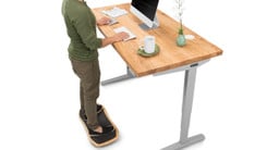 Gray UPLIFT V2 Standing Desk Frame with natural ash solid wood desktop.